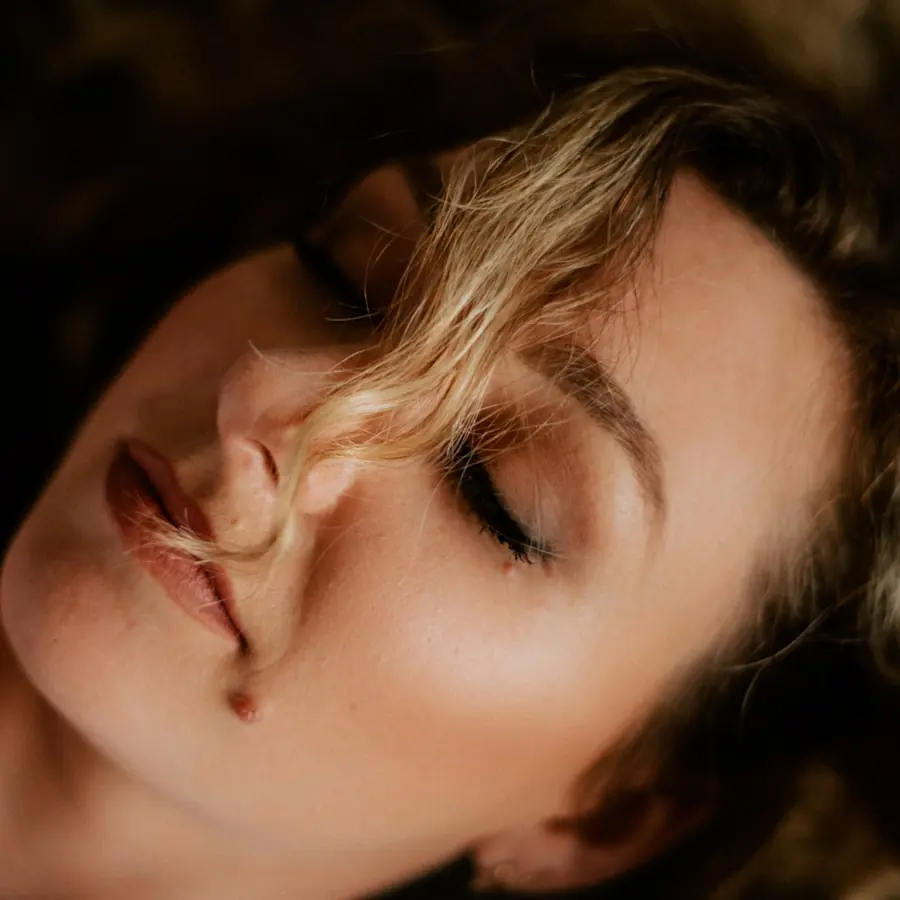 Woman with her eyes closed in warm sunlight, showing a healthy complexion